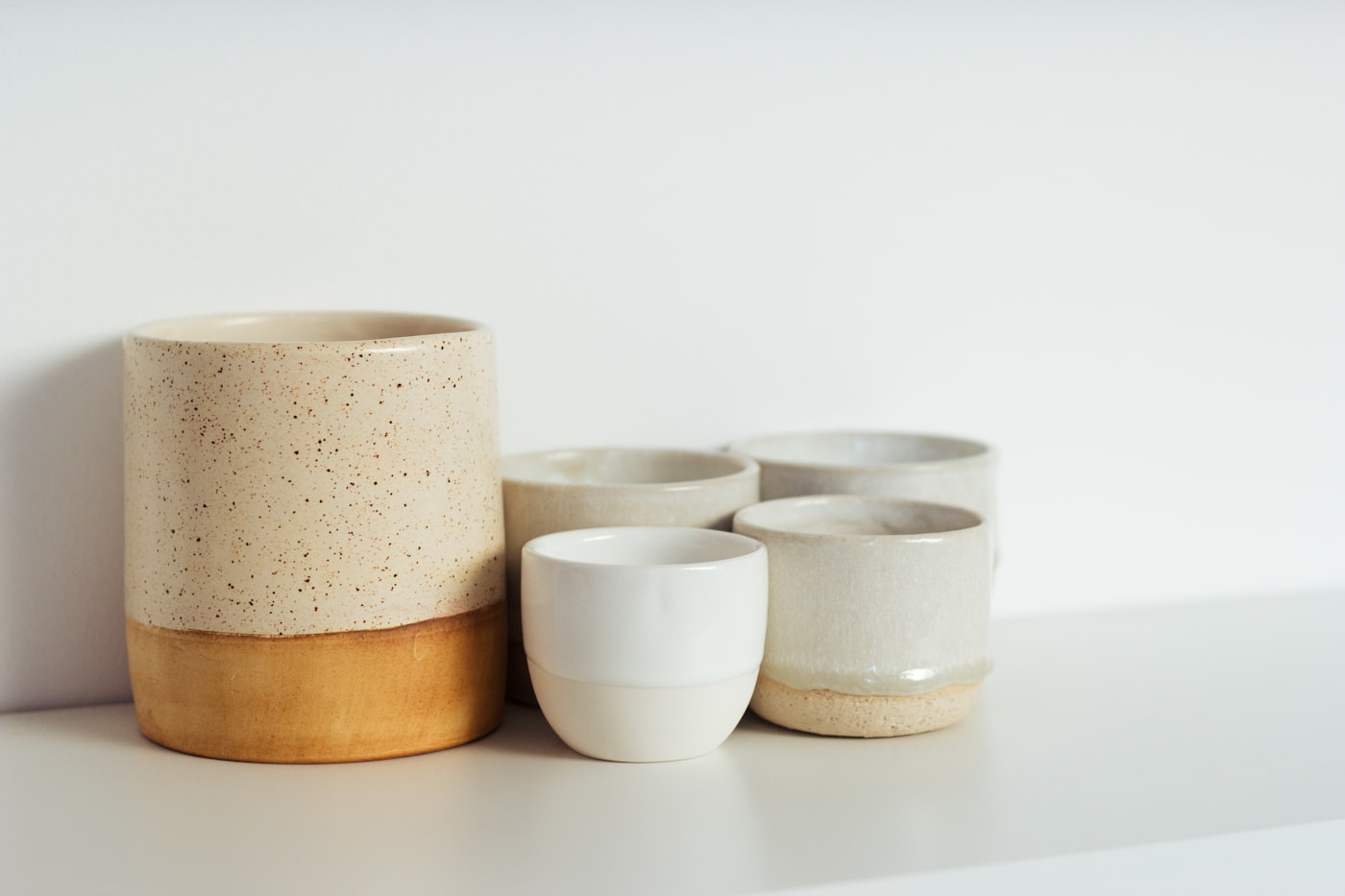 Artisan ceramic cups and vessels in muted cream and terracotta glazes