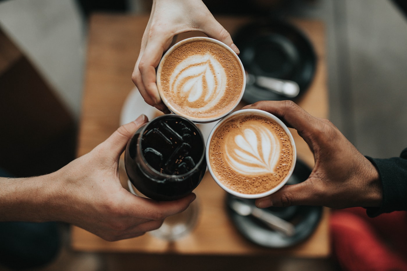 Barista serving fresh latte art coffees to friends