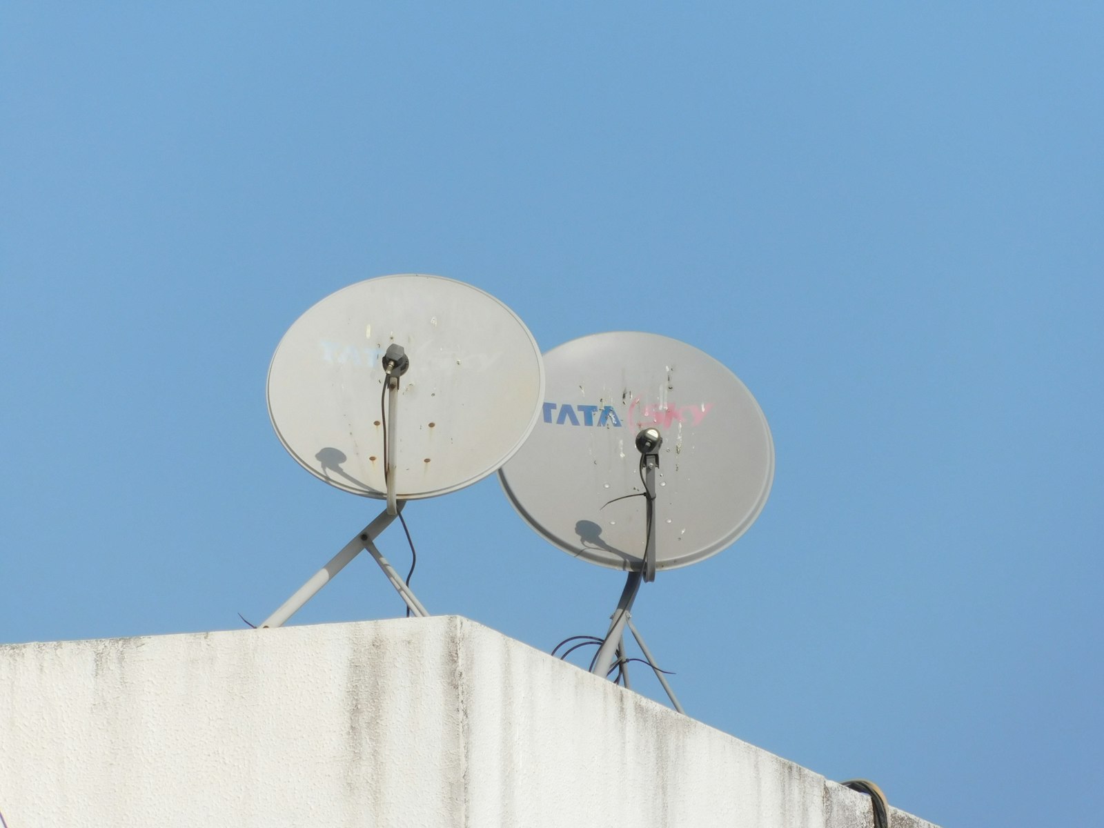 Rooftop satellite dishes against a clear blue sky