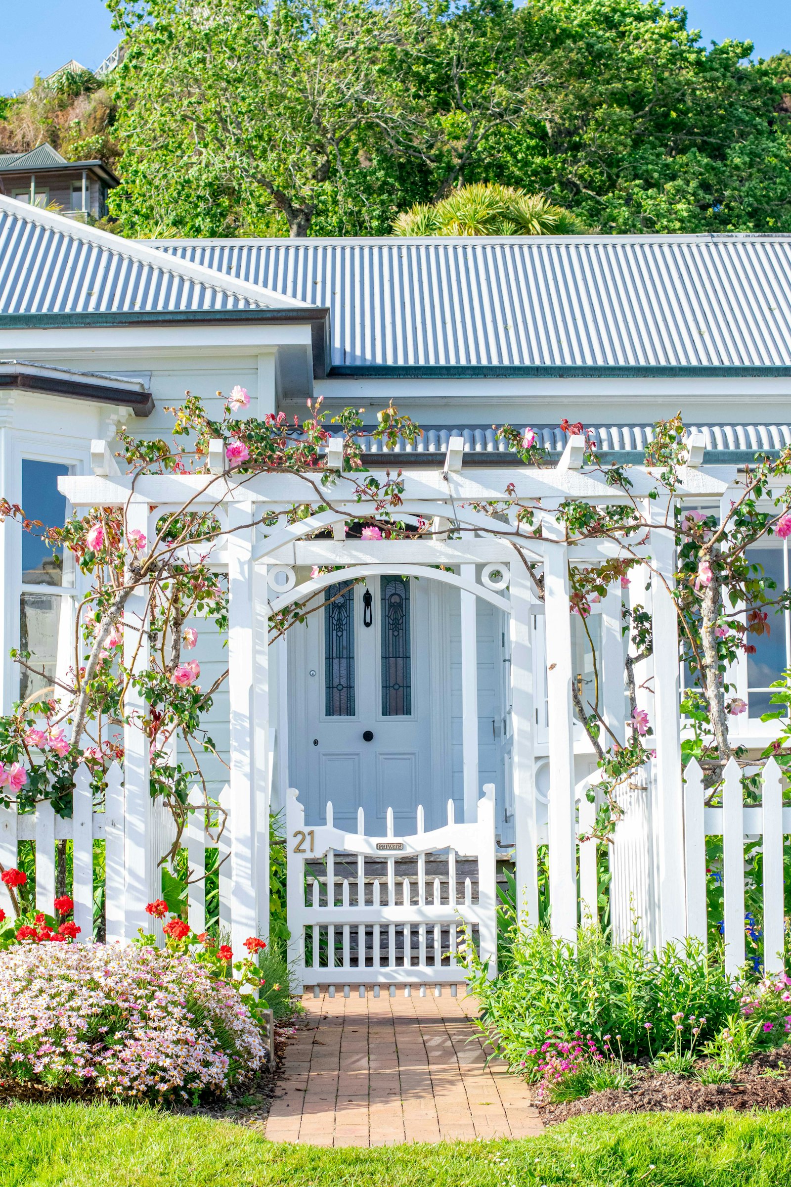 Traditional white picket garden fence and timber gate in front of a home
